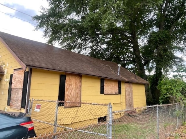 view of home's exterior with a shingled roof and fence