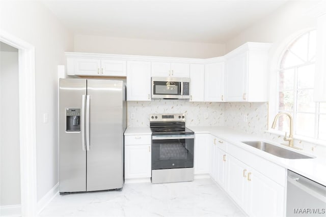kitchen with stainless steel appliances, a sink, white cabinets, and light countertops