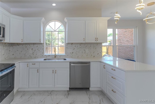 kitchen with stainless steel appliances, a sink, a peninsula, recessed lighting, and white cabinetry
