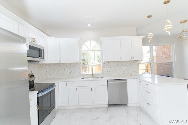 kitchen featuring appliances with stainless steel finishes, a sink, a peninsula, backsplash, and recessed lighting