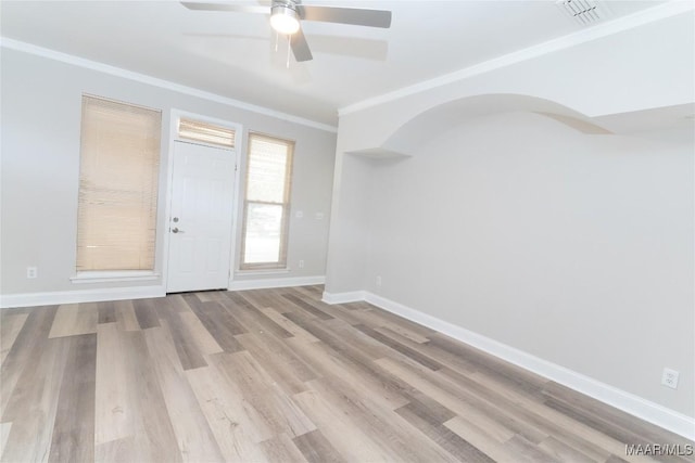 empty room with crown molding, a ceiling fan, wood finished floors, and baseboards