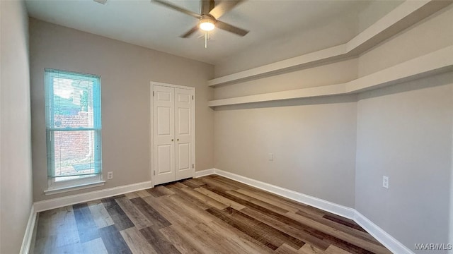 unfurnished room featuring a ceiling fan, dark wood finished floors, and baseboards