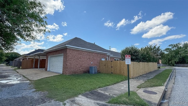view of side of home featuring a garage, brick siding, driveway, a gate, and central AC unit