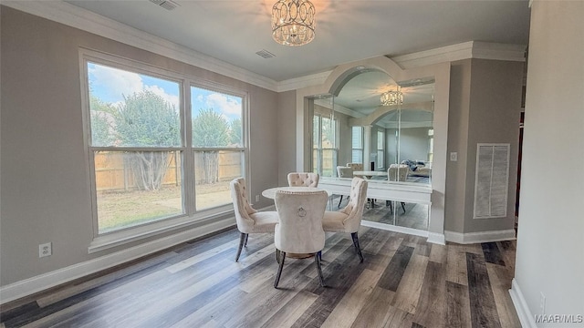 dining room with arched walkways, a chandelier, baseboards, crown molding, and wood finished floors