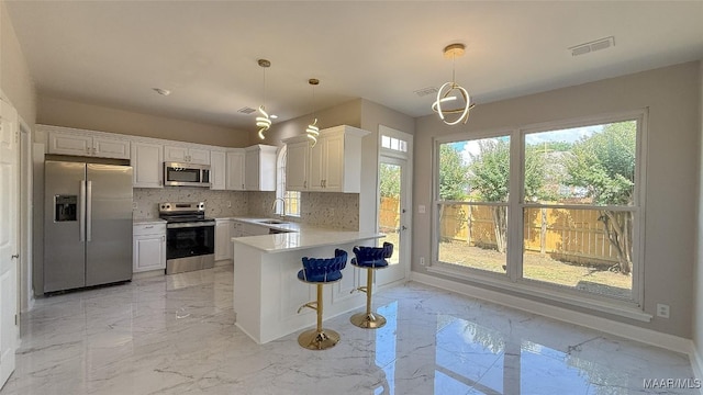 kitchen with stainless steel appliances, a sink, light marble finish floors, and light countertops