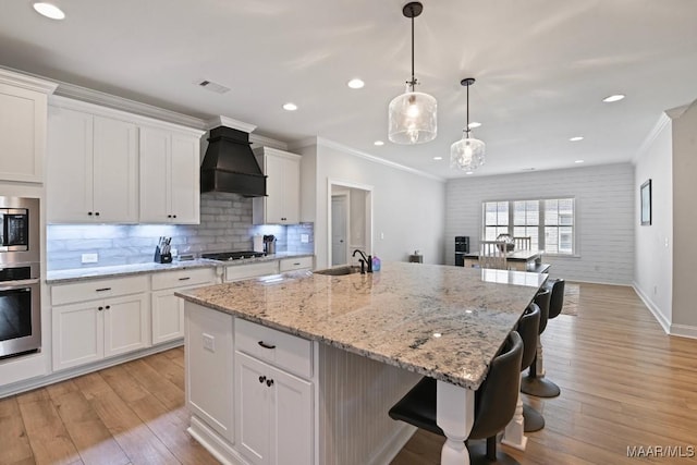 1430 Wildlife Way, Prattville, AL 36066 - kitchen featuring custom exhaust hood, appliances with stainless steel finishes, a sink, light wood-type flooring, and white cabinets