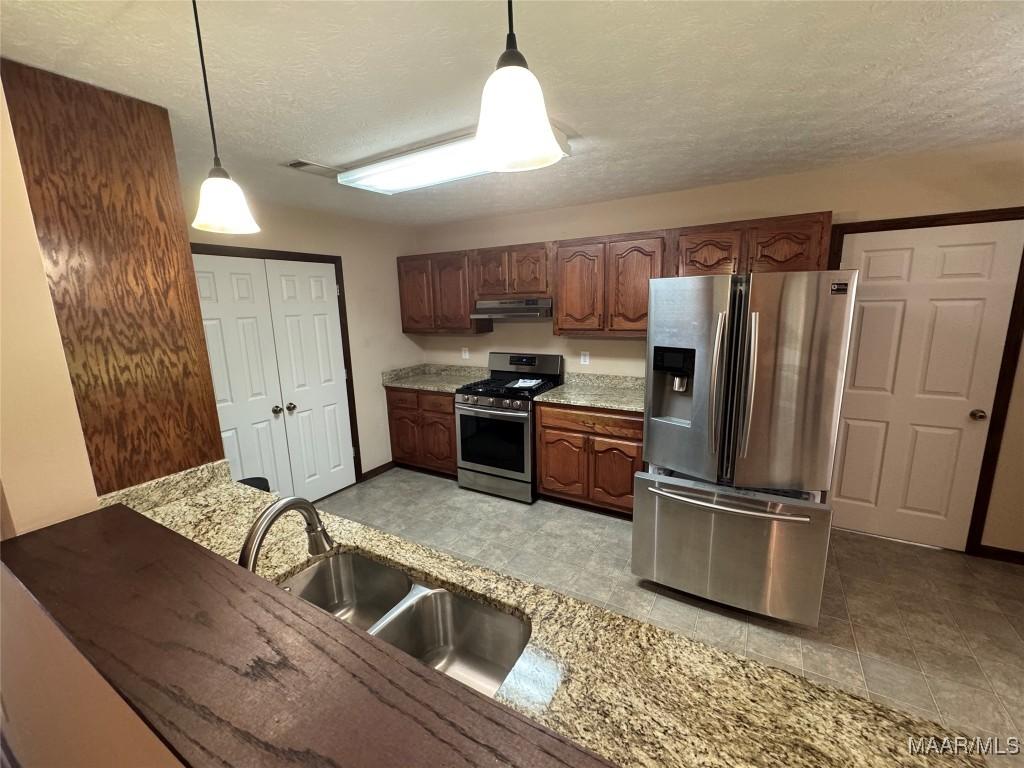 4030 Willowbrook Dr, Millbrook, AL 36054 - kitchen featuring appliances with stainless steel finishes, a textured ceiling, pendant lighting, a sink, and under cabinet range hood
