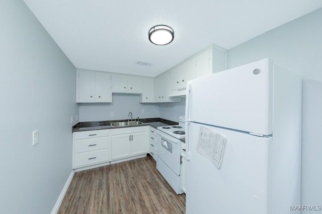 kitchen featuring white appliances, a sink, under cabinet range hood, dark wood finished floors, and white cabinets