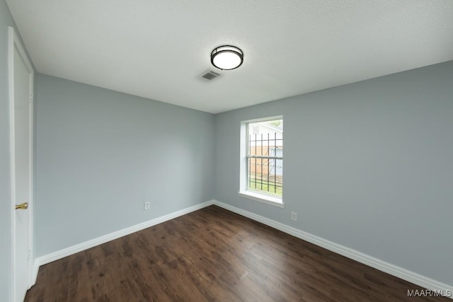 unfurnished room featuring dark wood-type flooring and baseboards