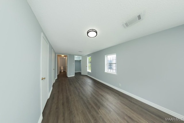 unfurnished bedroom with dark wood-style flooring, baseboards, and a textured ceiling