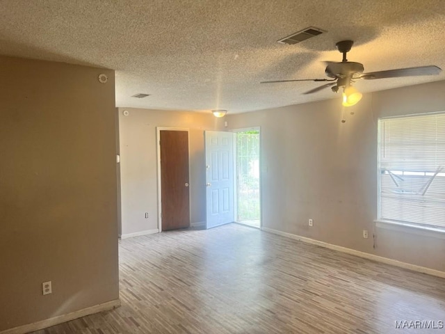unfurnished room with a textured ceiling, wood finished floors, baseboards, and ceiling fan