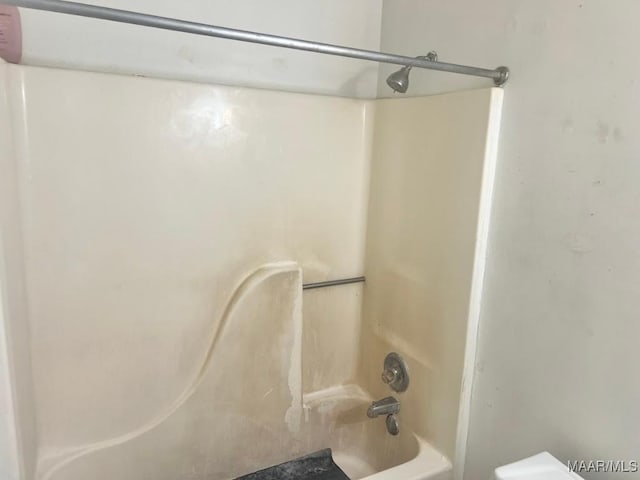 bathroom with bathing tub / shower combination and toilet