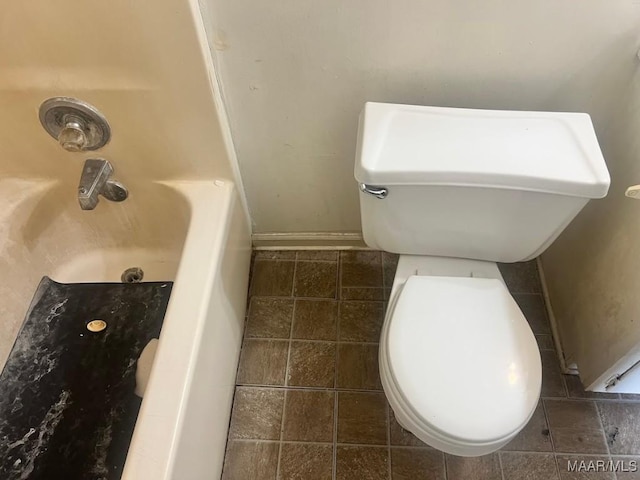 bathroom with a bathtub, toilet, and baseboards