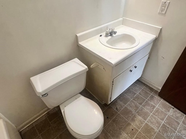half bath featuring vanity, toilet, and baseboards