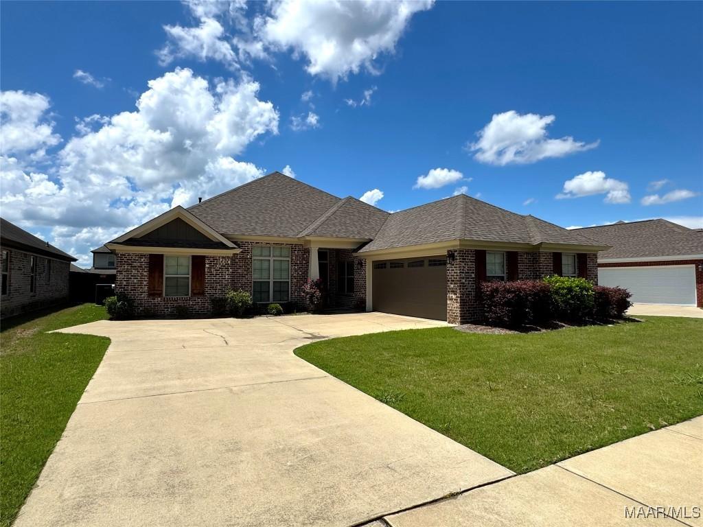 view of front facade with brick siding, an attached garage, and a front yard