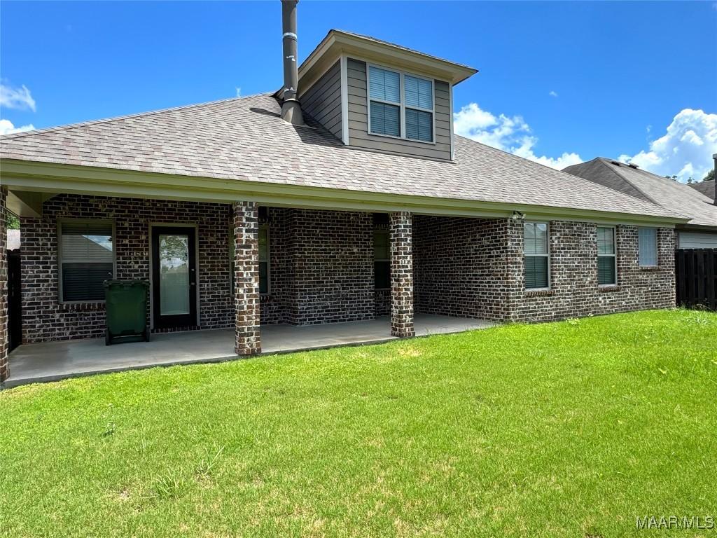 rear view of house with a patio area, brick siding, and roof with shingles
