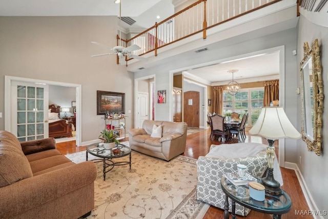 living area with baseboards, a chandelier, wood finished floors, and a towering ceiling