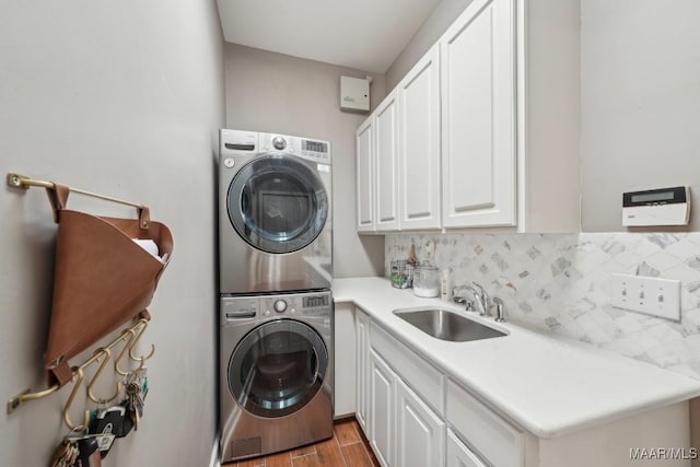 laundry room featuring stacked washing machine and dryer, cabinet space, and wood finished floors