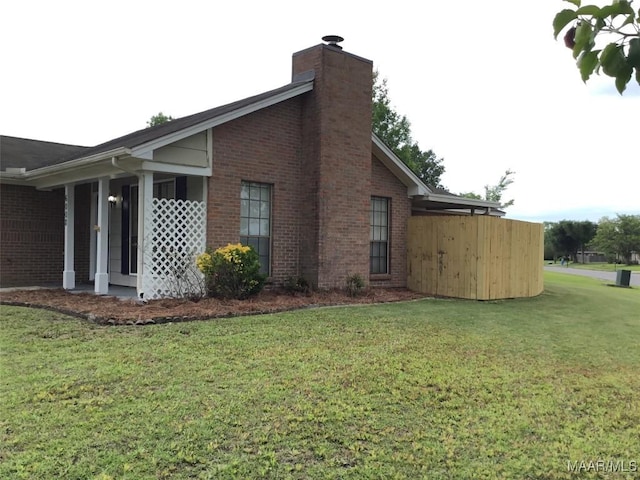 view of property exterior with a lawn, brick siding, and a chimney