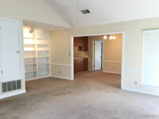 unfurnished living room with carpet, a chandelier, baseboards, and lofted ceiling