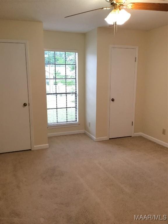 unfurnished room featuring light carpet, a ceiling fan, and baseboards