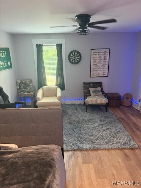 living area with a ceiling fan and wood finished floors