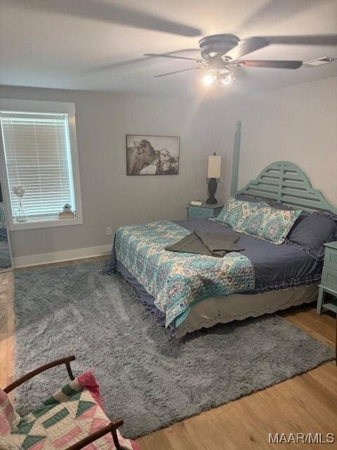 bedroom featuring wood finished floors, baseboards, and ceiling fan