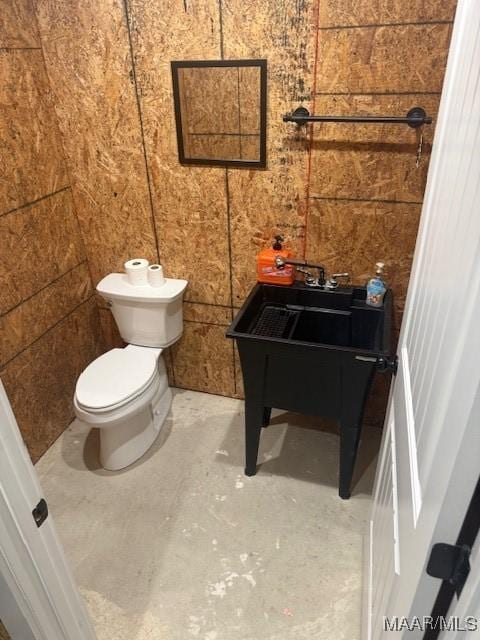 bathroom with toilet and unfinished concrete floors
