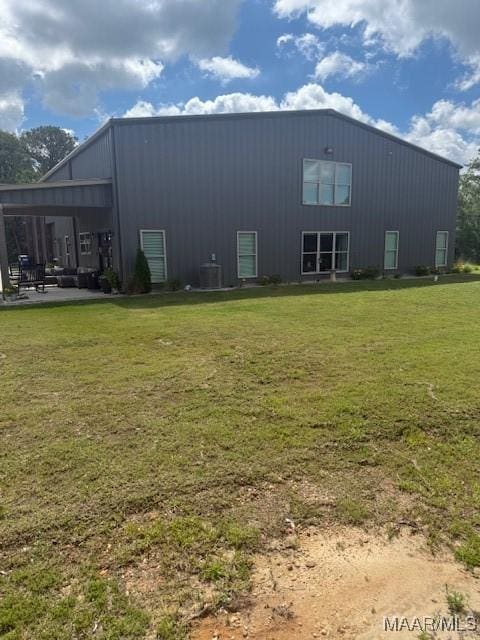 back of house featuring a lawn, central air condition unit, and board and batten siding
