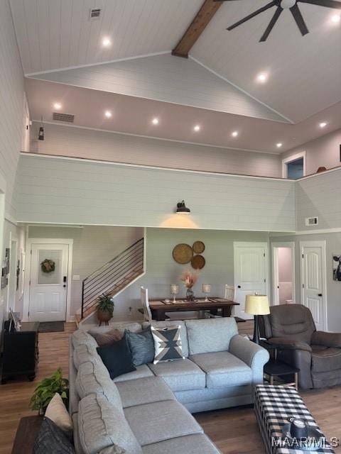 living room featuring high vaulted ceiling, wood finished floors, ceiling fan, beam ceiling, and stairway