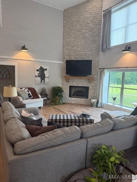 living area featuring high vaulted ceiling, wood finished floors, plenty of natural light, and a fireplace