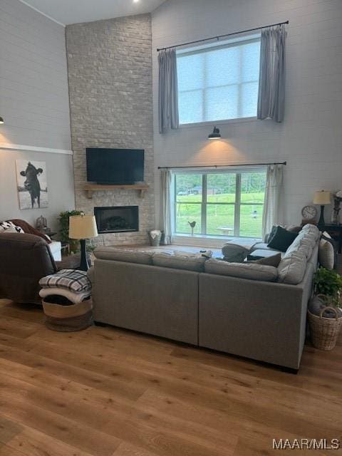 living area with a high ceiling, wood finished floors, and a large fireplace