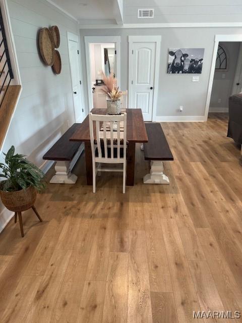 dining area with light wood finished floors, ornamental molding, and baseboards