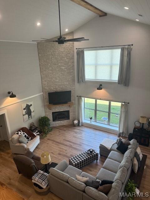 living room with wood finished floors, beamed ceiling, ceiling fan, high vaulted ceiling, and a fireplace