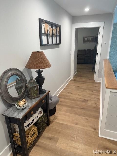 hallway with light wood finished floors, baseboards, and recessed lighting