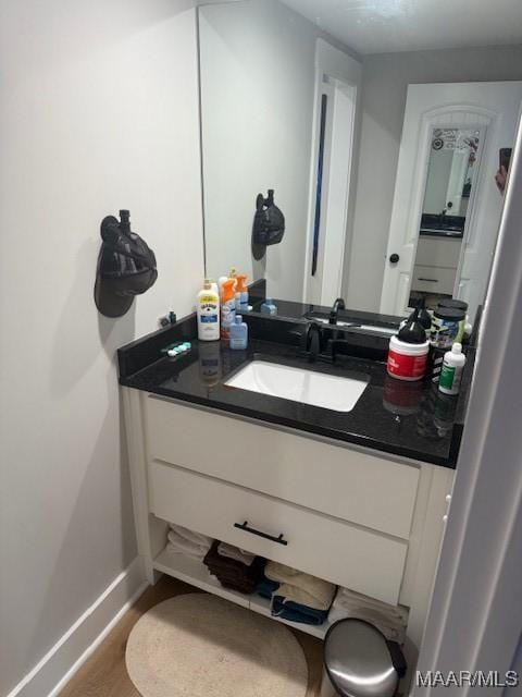 bathroom with baseboards, wood finished floors, and vanity