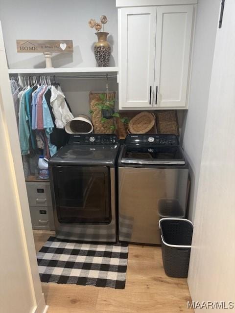 laundry area featuring independent washer and dryer, cabinet space, and light wood-type flooring