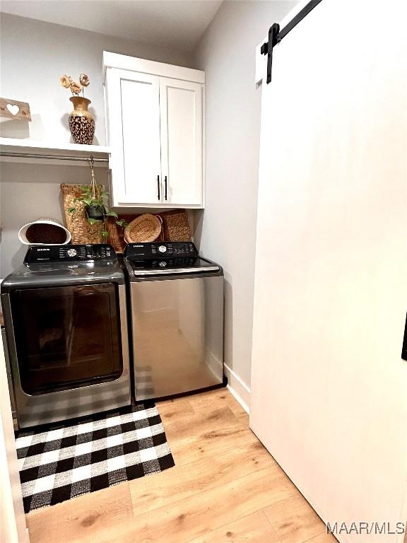 2533 Weldon Rd, Tallassee, AL 36078 - laundry room with cabinet space, washing machine and clothes dryer, light wood finished floors, and a barn door