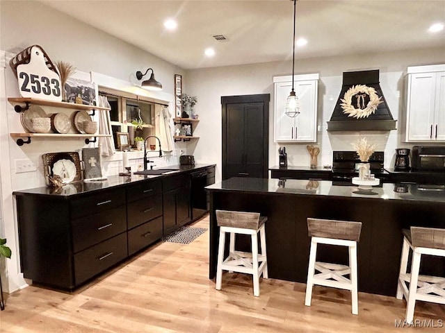 2533 Weldon Rd, Tallassee, AL 36078 - kitchen featuring open shelves, custom range hood, dark countertops, a breakfast bar, and white cabinetry
