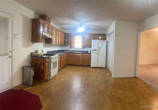 176 Lawrence Cv, Valley Grande, AL 36703 - kitchen with white appliances, a sink, under cabinet range hood, dark countertops, and hardwood / wood-style floors