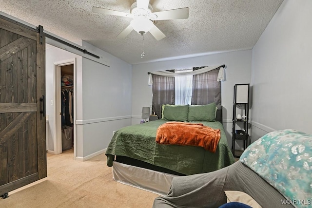 6221 Hinchcliff Dr, Montgomery, AL 36117 - bedroom featuring a barn door, carpet flooring, a spacious closet, a textured ceiling, and a ceiling fan