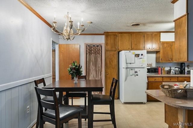 6221 Hinchcliff Dr, Montgomery, AL 36117 - kitchen with freestanding refrigerator, brown cabinetry, a textured ceiling, a chandelier, and crown molding