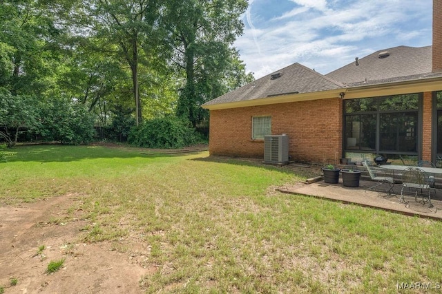 view of grassy yard featuring central air condition unit and a patio