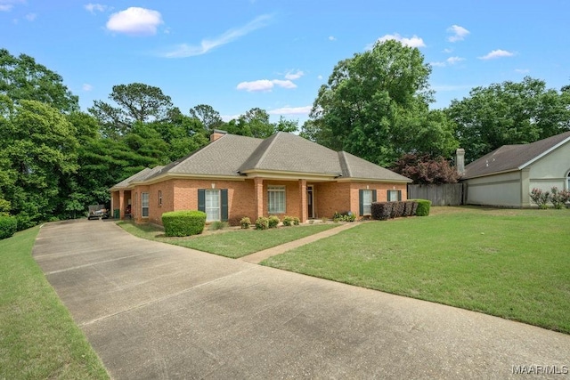 view of front of home with a front lawn, concrete driveway, brick siding, and roof with shingles