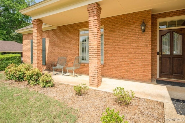 doorway to property with brick siding and covered porch