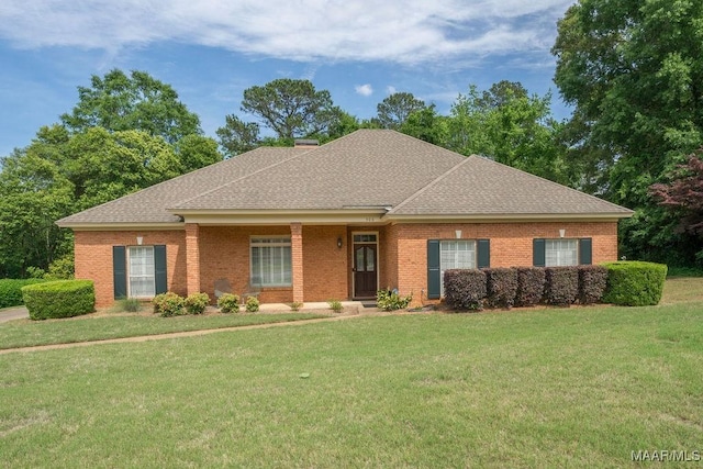 view of front facade featuring a shingled roof, a front yard, and brick siding