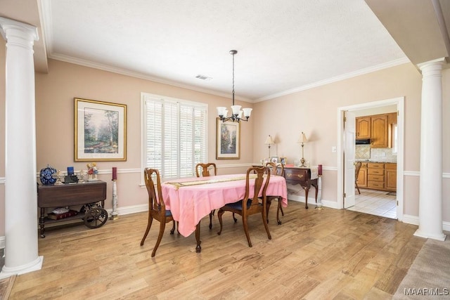 dining room featuring ornate columns, light wood-style floors, a chandelier, ornamental molding, and baseboards