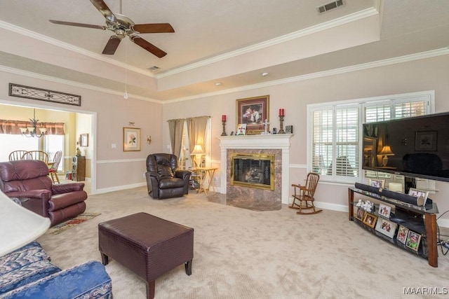 living area with a tray ceiling, carpet, a premium fireplace, a chandelier, and crown molding