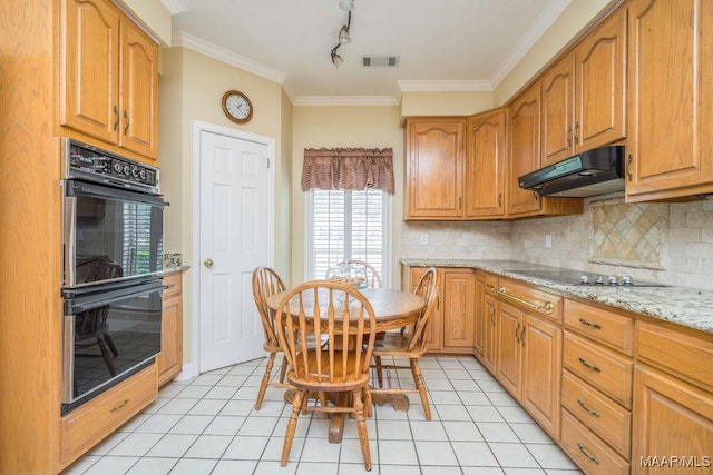 kitchen with under cabinet range hood, black appliances, ornamental molding, tasteful backsplash, and light tile patterned floors