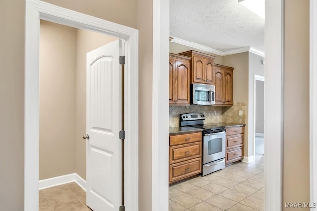 612 Coleman Way, Prattville, AL 36067 - kitchen featuring appliances with stainless steel finishes, light tile patterned floors, decorative backsplash, dark countertops, and brown cabinetry